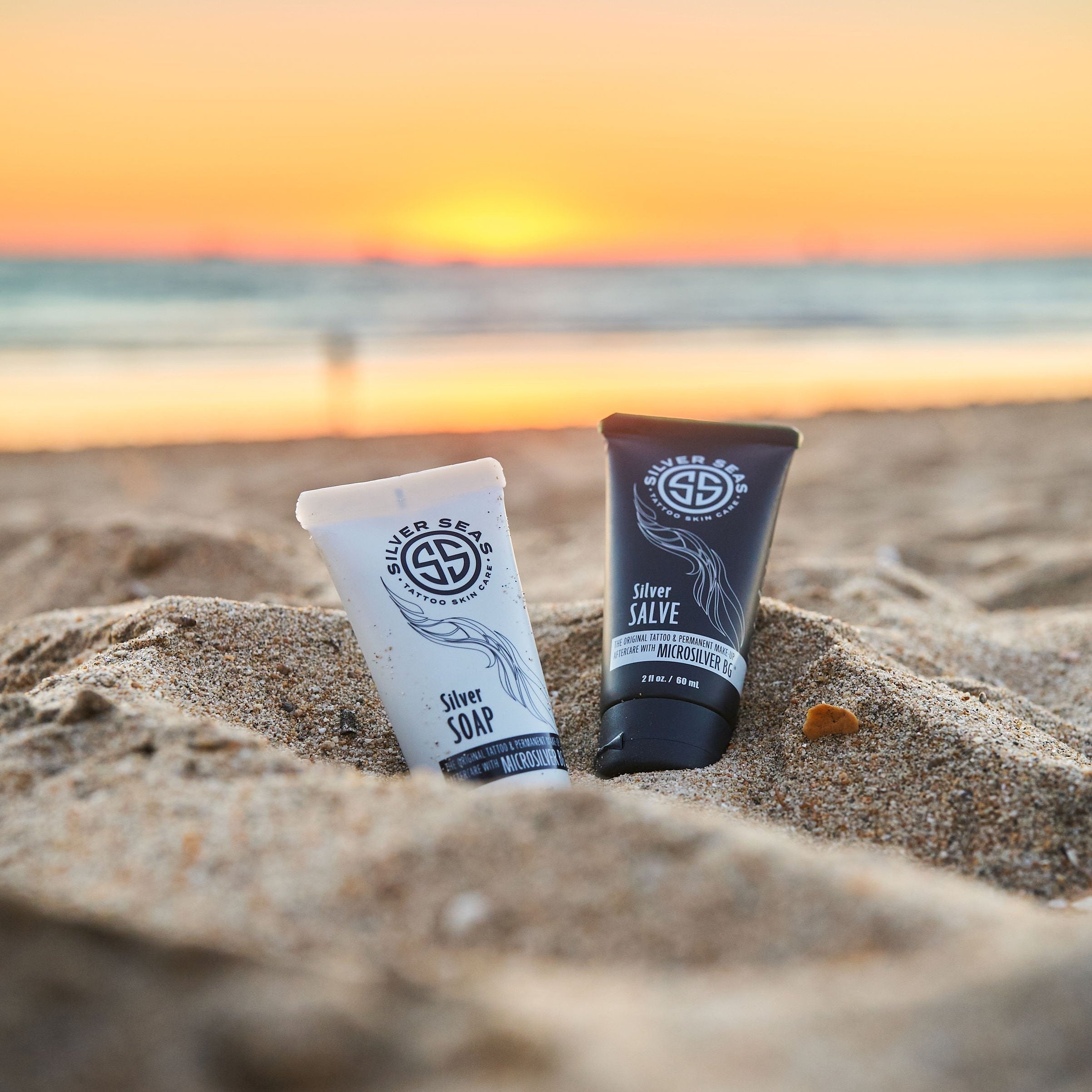 Silver Seas Skincare tubes with Microsilver BG™ laying in beach sand.